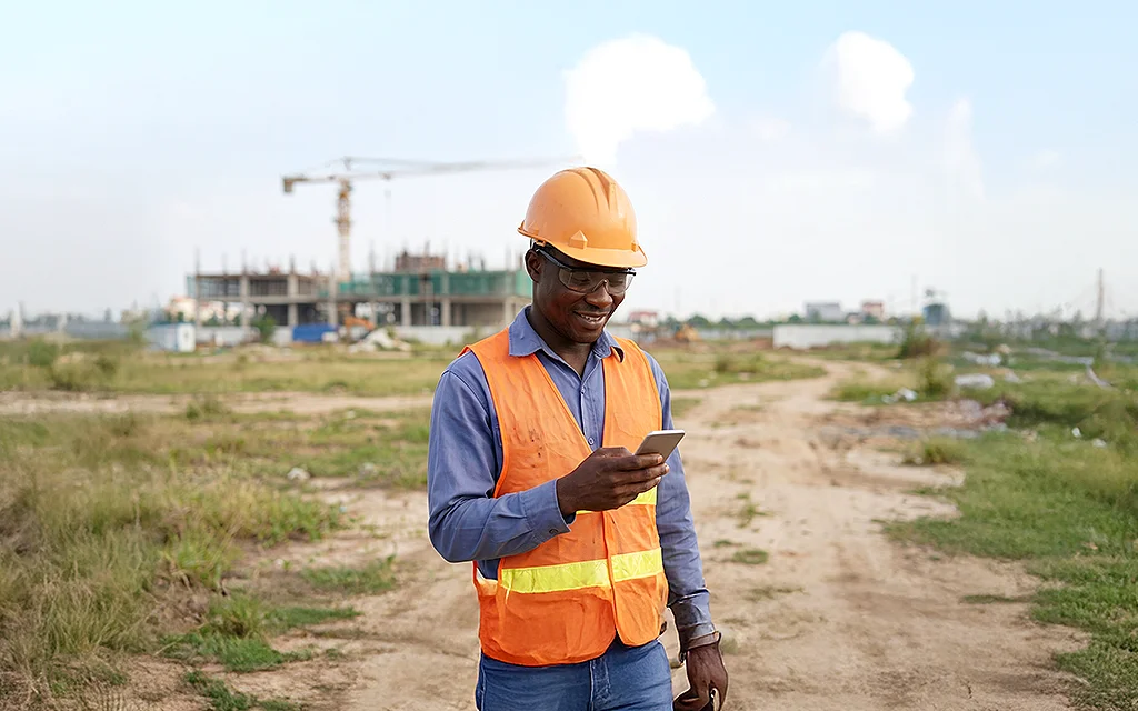 Construction worker checking remittance transfer on their phone.