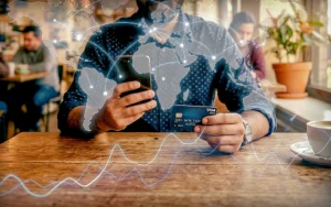 Person using a smartphone and a credit card with a global network overlay, illustrating the effect of remittances on economic growth.